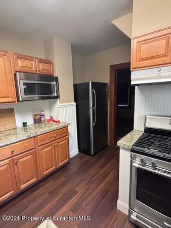 a kitchen with granite countertop stainless steel appliances a stove microwave and refrigerator