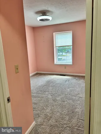 a view of an empty room with closet and a window