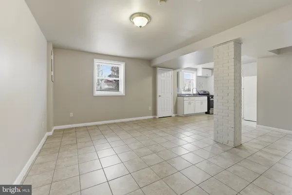 an empty room with kitchen view and natural light