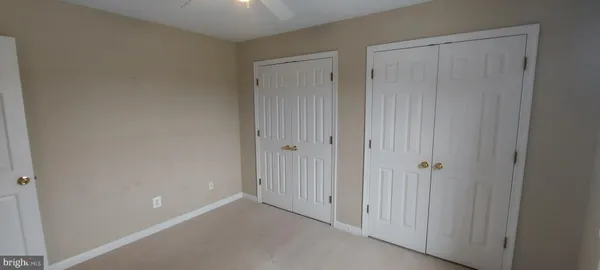 an empty room with windows and chandelier fan