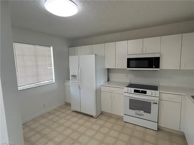a kitchen with white cabinets and white appliances