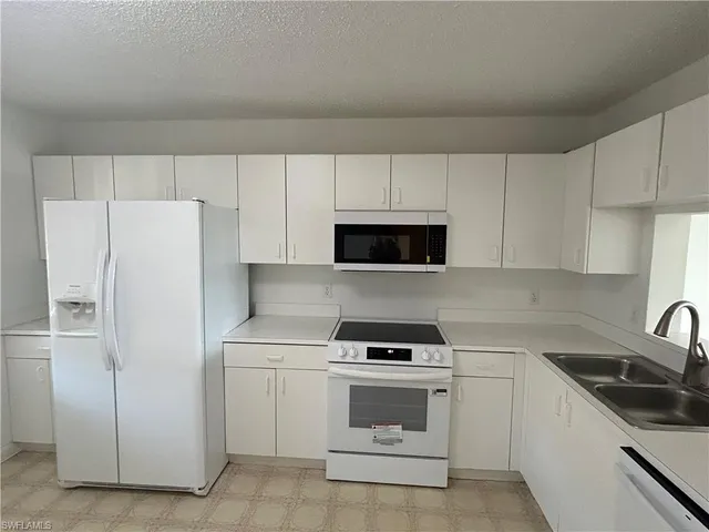 a kitchen with white cabinets and white appliances
