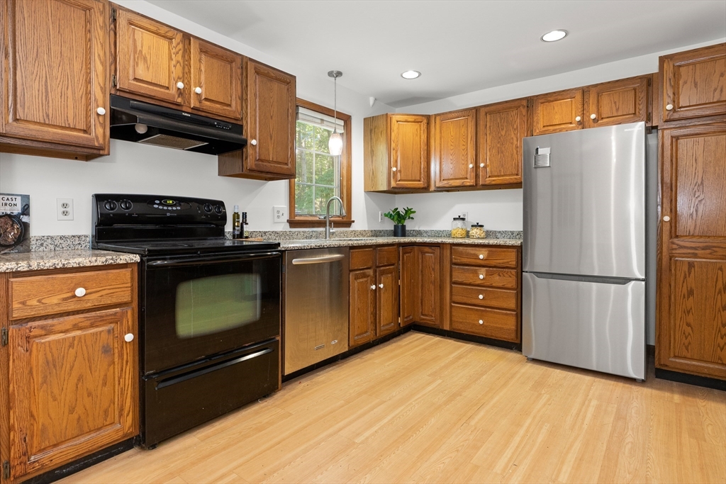 31 Kimball Road Amesbury, MA 01913 - Photo 6 of 40 a kitchen with stainless steel appliances granite countertop a stove top oven a refrigerator a sink and dishwasher with wooden floor