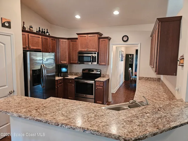 a kitchen with stainless steel appliances granite countertop a stove refrigerator and a microwave