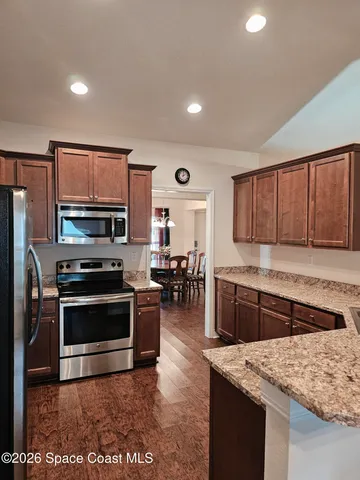a kitchen with stainless steel appliances granite countertop a refrigerator a stove and a sink