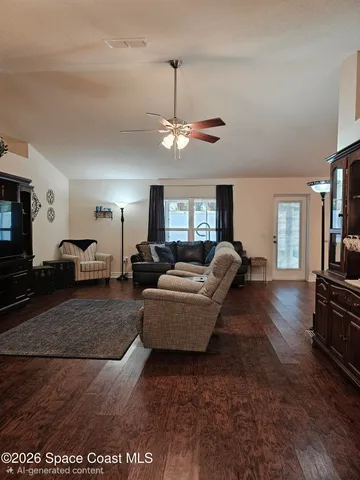 a living room with furniture a ceiling fan and a flat screen tv