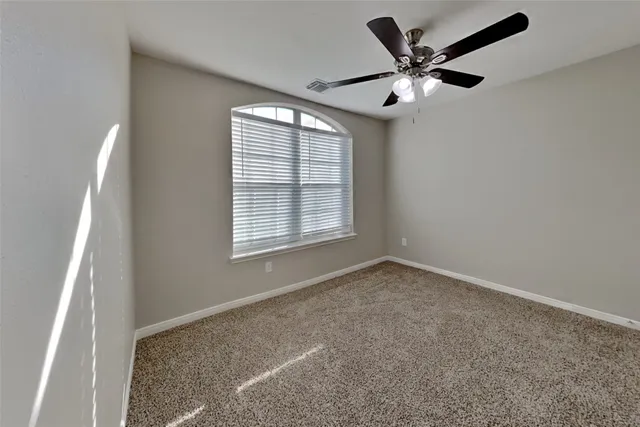 an empty room with a ceiling fan and window