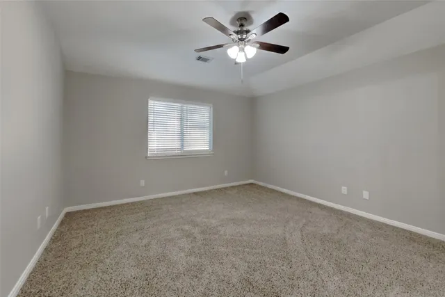 an empty room with a chandelier fan and windows