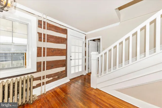 a view of an empty room with wooden floor and windows