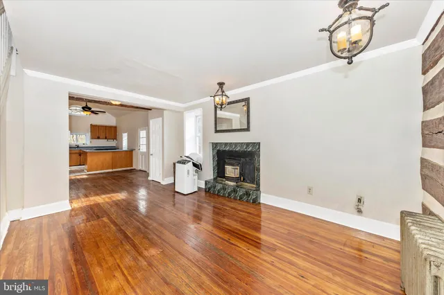 a view of a room with wooden floor fire place and windows
