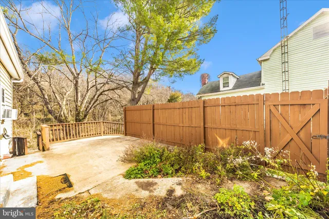 a view of backyard with large tree and wooden fence