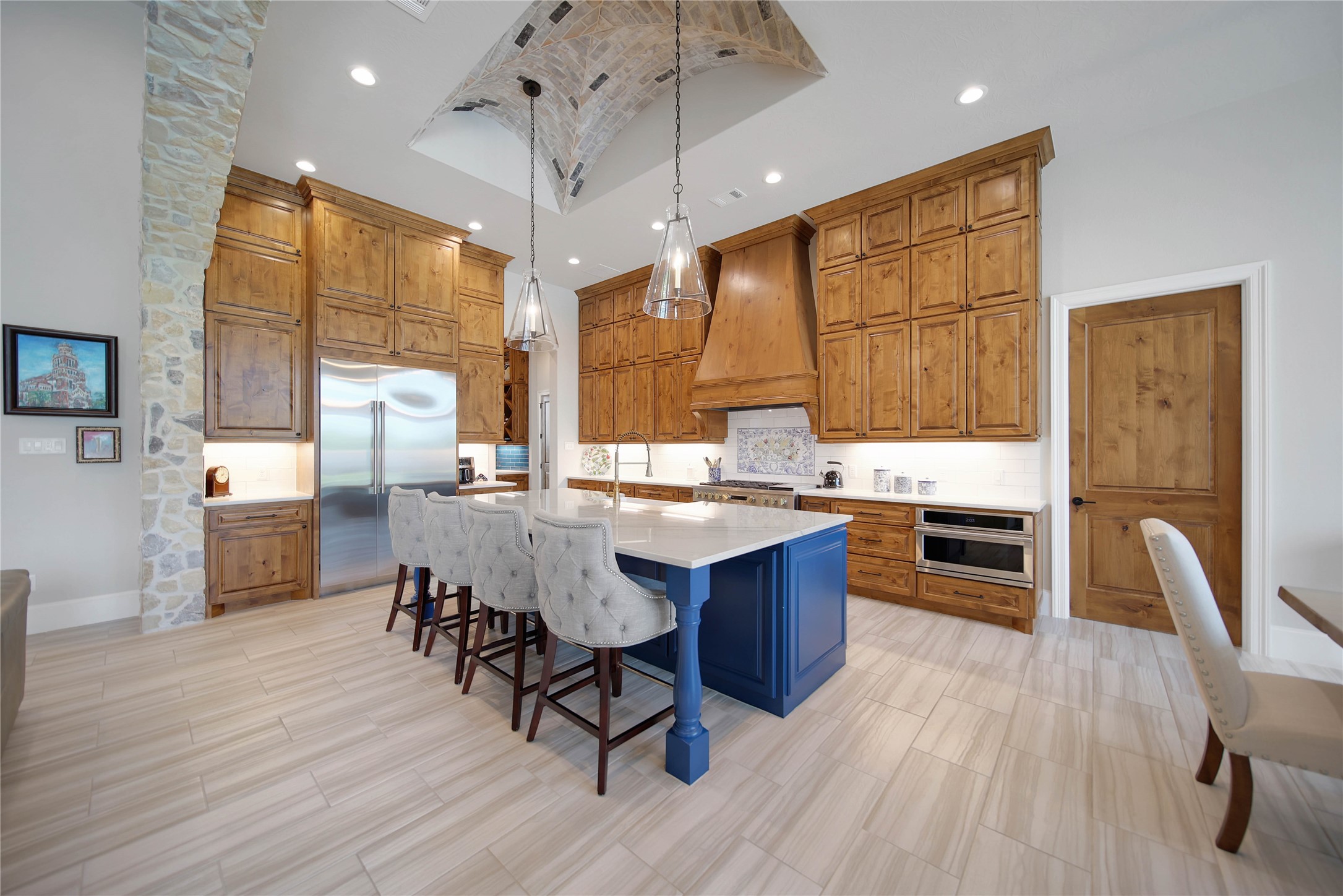 24718 Shadow Pond Spring, TX 77389 - Photo 13 of 49 Spacious kitchen with elegant wood cabinetry, a striking blue island, and high-end stainless steel appliances, perfect for culinary enthusiasts.