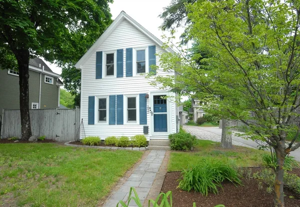 a front view of a house with a yard and large trees