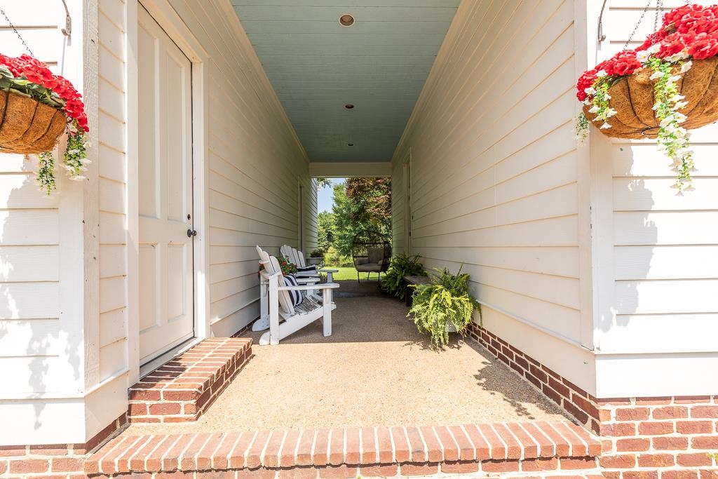 1915 Teague Store Road Somerville, TN 38068 - Photo 13 of 38 Covered outdoor corridor featuring white siding, a blue ceiling, and a brick foundation