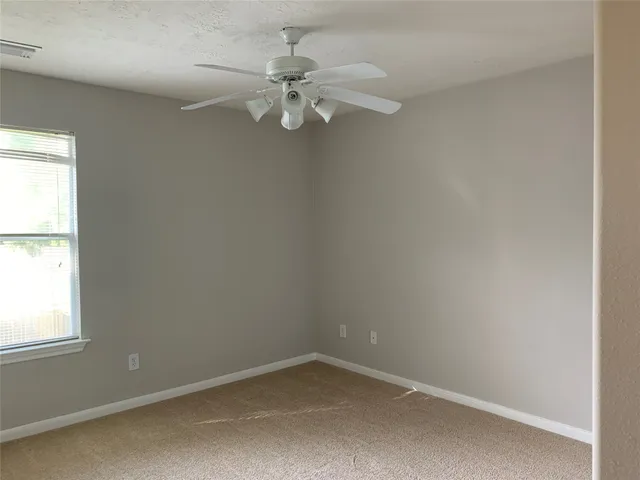 an empty room with a window and a fan