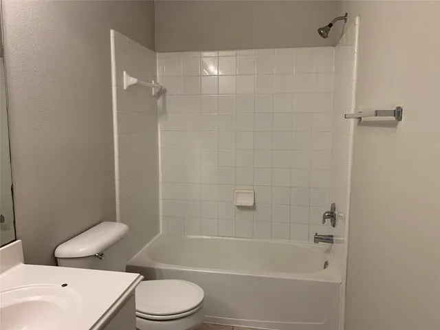 a white toilet and tub sitting next to a bathroom sink
