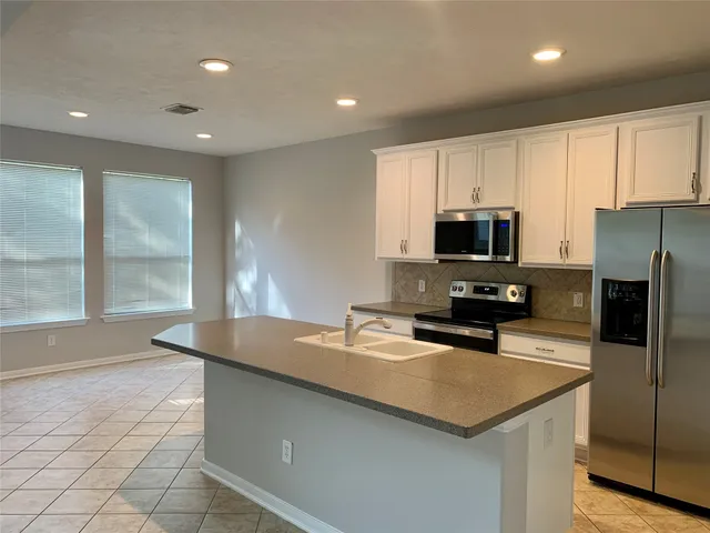 a kitchen with kitchen island a counter top space appliances and cabinets