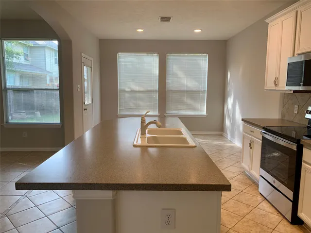 a view of a kitchen with a stove wooden cabinets and a counter top space