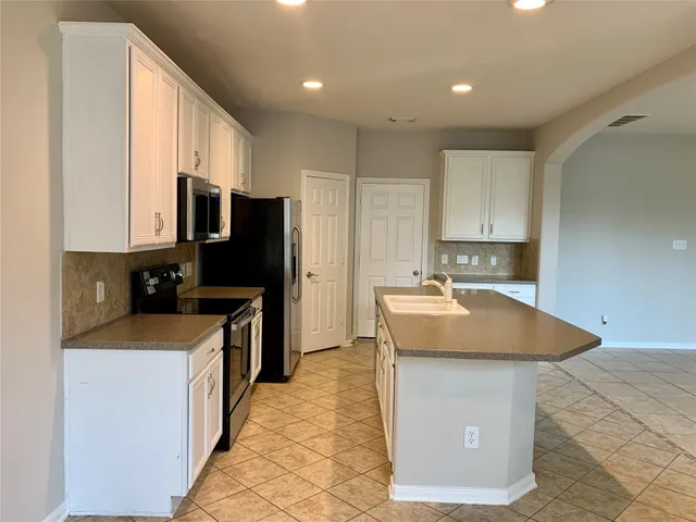 a kitchen with stainless steel appliances granite countertop a sink a stove and a refrigerator