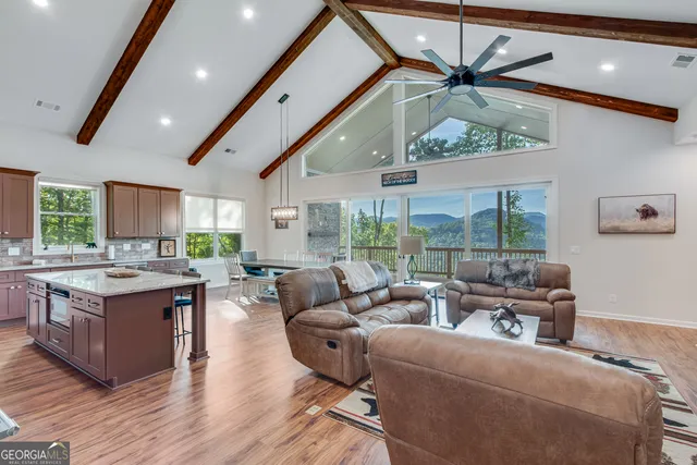a living room with furniture kitchen area and a large window