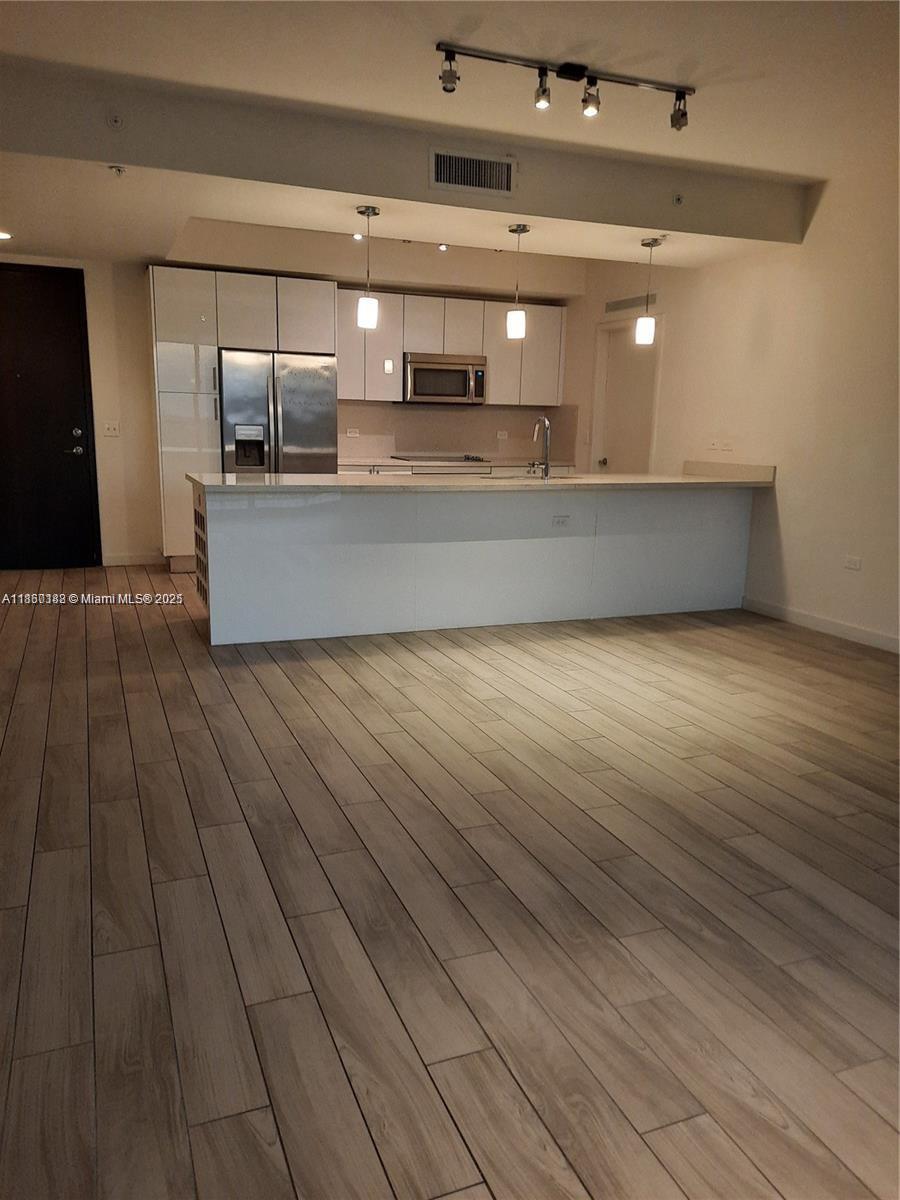 999 Southwest 1st Avenue, Unit 2705 Miami, FL 33130 - Photo 21 of 24 a large kitchen with stainless steel appliances a large counter top a sink and a stove