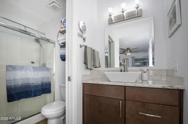 a bathroom with a granite countertop sink toilet mirror and shower