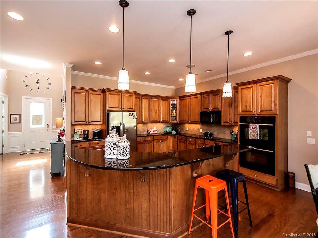 735 Quicksilver Trail Fort Mill, SC 29708 - Photo 4 of 20 a kitchen with stainless steel appliances granite countertop a stove top oven a refrigerator a sink a dining table and chairs with wooden floor