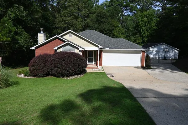 a front view of a house with a garden and trees