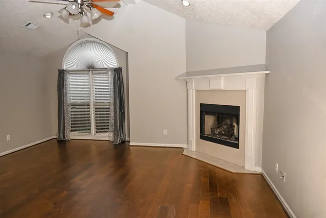 an empty room with wooden floor fireplace and windows