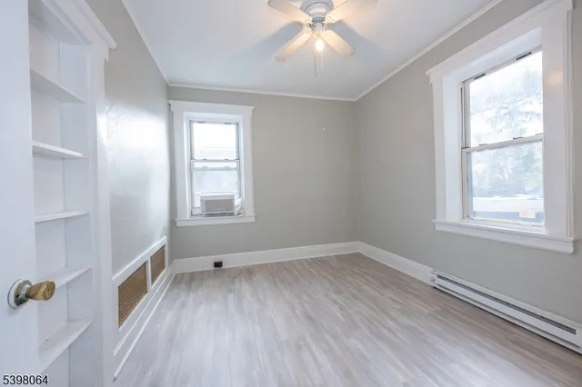 a view of an empty room with a window and wooden floor
