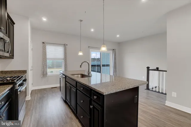 a kitchen with granite countertop a stove and a wooden floor