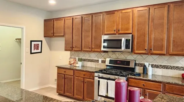 a kitchen with stainless steel appliances granite countertop a stove a microwave and a sink