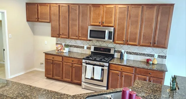 a kitchen with stainless steel appliances granite countertop a stove a sink and a microwave