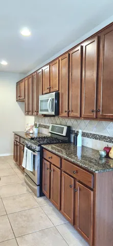 a kitchen with stainless steel appliances granite countertop a stove a sink and a microwave