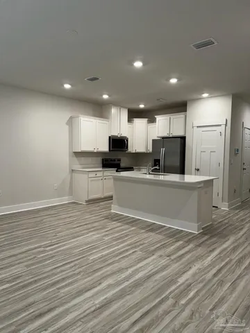 a view of kitchen with microwave stove refrigerator and cabinets