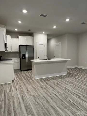 a large white kitchen with refrigerator stove a sink and dishwasher with wooden floor