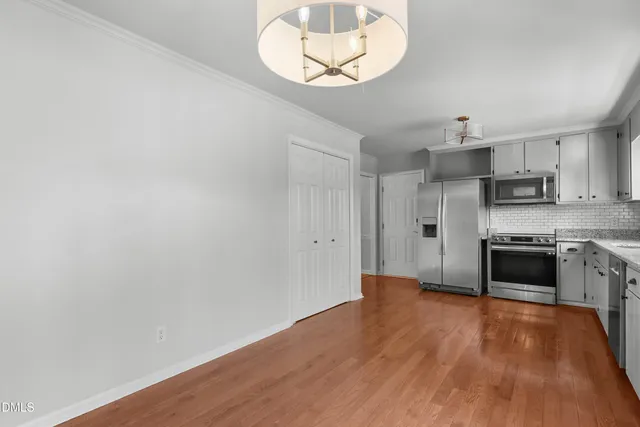 a view of kitchen with stainless steel appliances wooden floor and a refrigerator