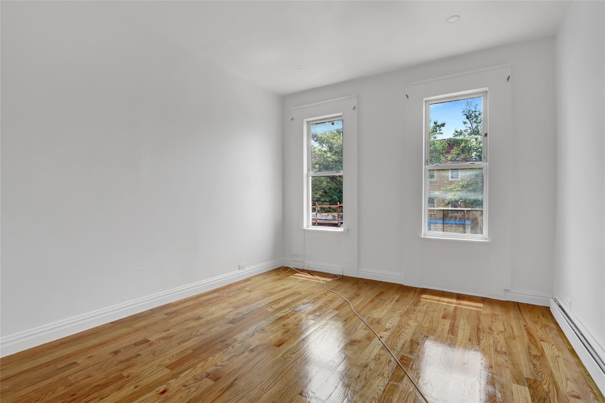 119-15 101st Avenue Queens, NY 11419 - Photo 6 of 20 Unfurnished room featuring a baseboard radiator, light wood-style floors, and healthy amount of natural light