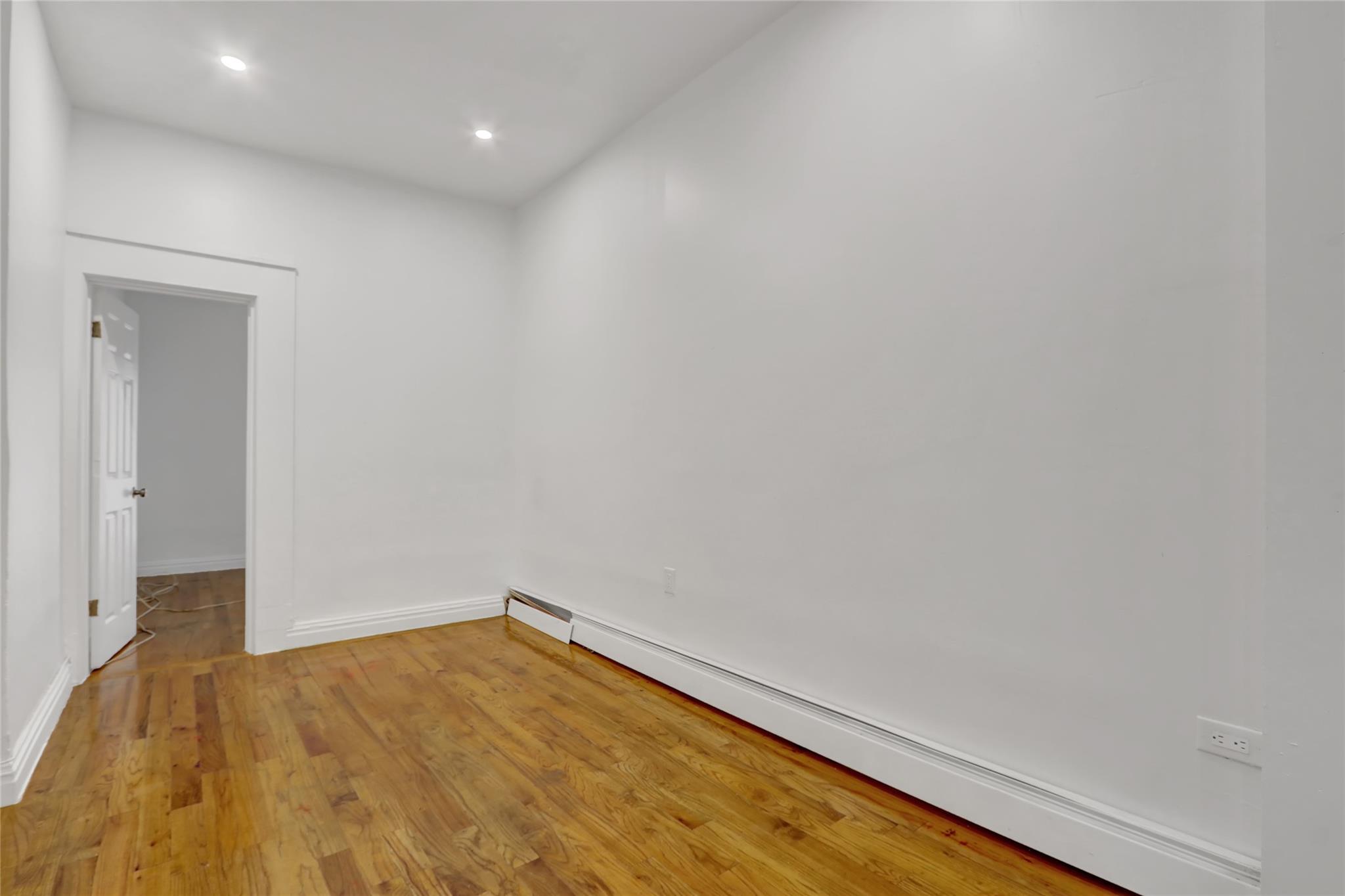 119-15 101st Avenue Queens, NY 11419 - Photo 7 of 20 Unfurnished room featuring a baseboard radiator, light wood-type flooring, and recessed lighting
