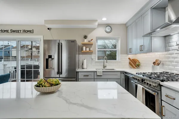 a kitchen with stainless steel appliances kitchen island granite countertop a sink stove and refrigerator