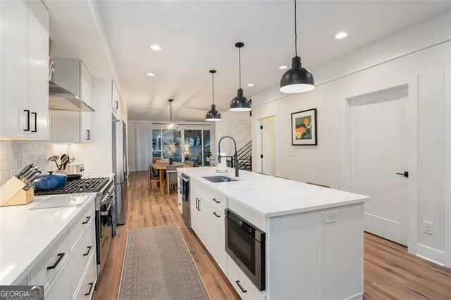 a large kitchen with kitchen island a stove a sink a refrigerator and a dining table with wooden floor