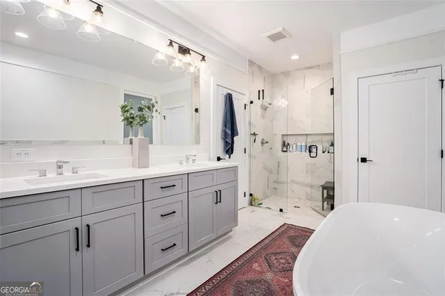 a spacious bathroom with double vanity sink a large mirror a shower and bathtub
