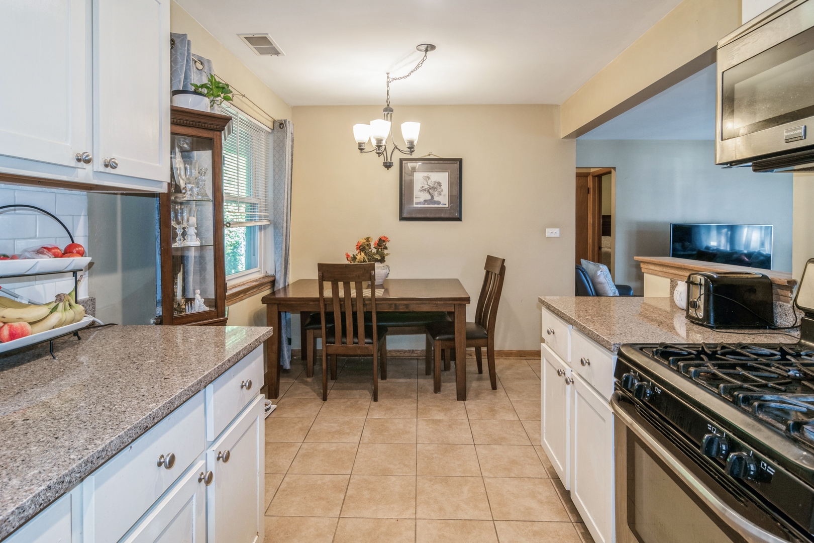 24 North Delaplaine Road Riverside, IL 60546 - Photo 6 of 11 a kitchen with stainless steel appliances granite countertop a stove a sink dishwasher a dining table and chairs with wooden floor