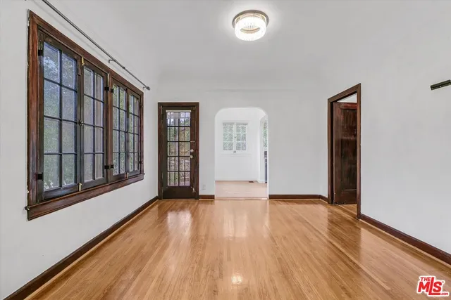 a view of an empty room with glass door and wooden floor