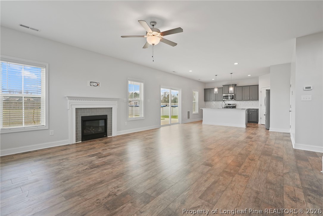 5150 J T Matthews Road Godwin, NC 28344 - Photo 17 of 50 a view of a livingroom with a fireplace a ceiling fan a kitchen microwave and a refrigerator