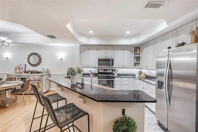 a kitchen with stainless steel appliances granite countertop a sink and a refrigerator