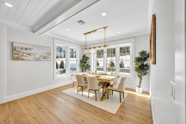 a dining room with wooden floor a chandelier a glass table and chairs