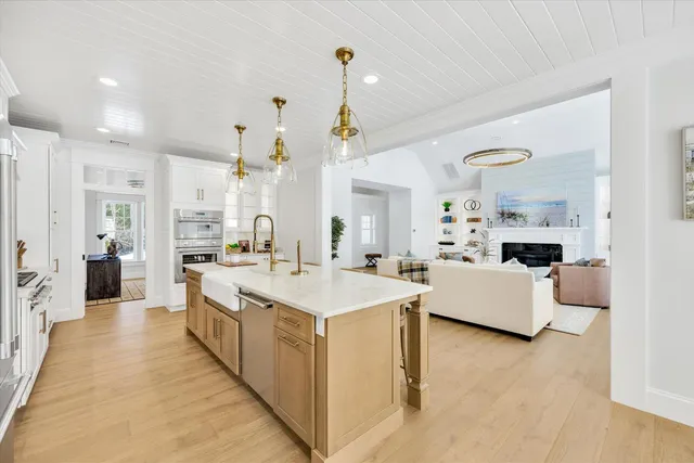 a large white kitchen with kitchen island a stove a sink a couch and a living room view