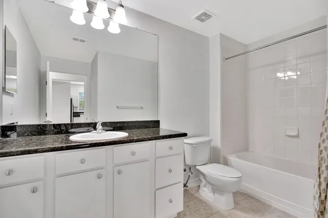 a bathroom with a granite countertop sink a toilet and bathtub