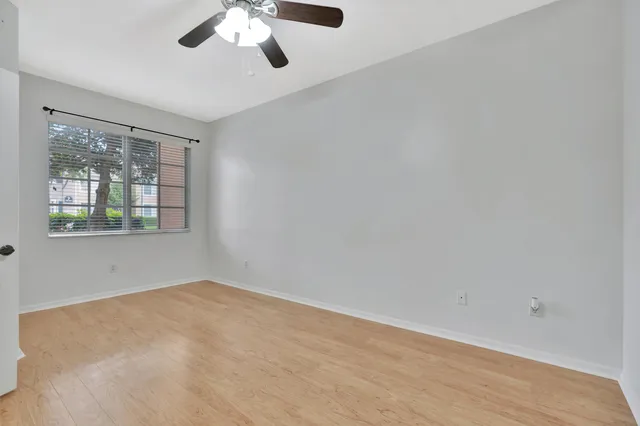 an empty room with a window and a ceiling fan